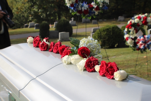 Casket in a cemetery with flowers on top