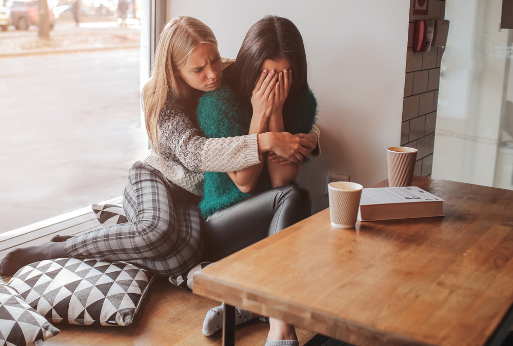 Young woman being comforted by her friend